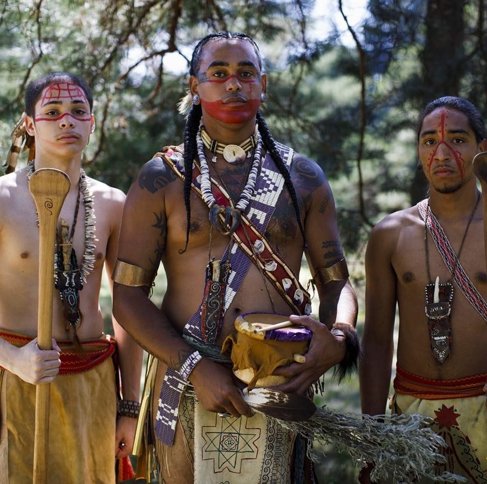 Three native men dressed in traditional attire. 