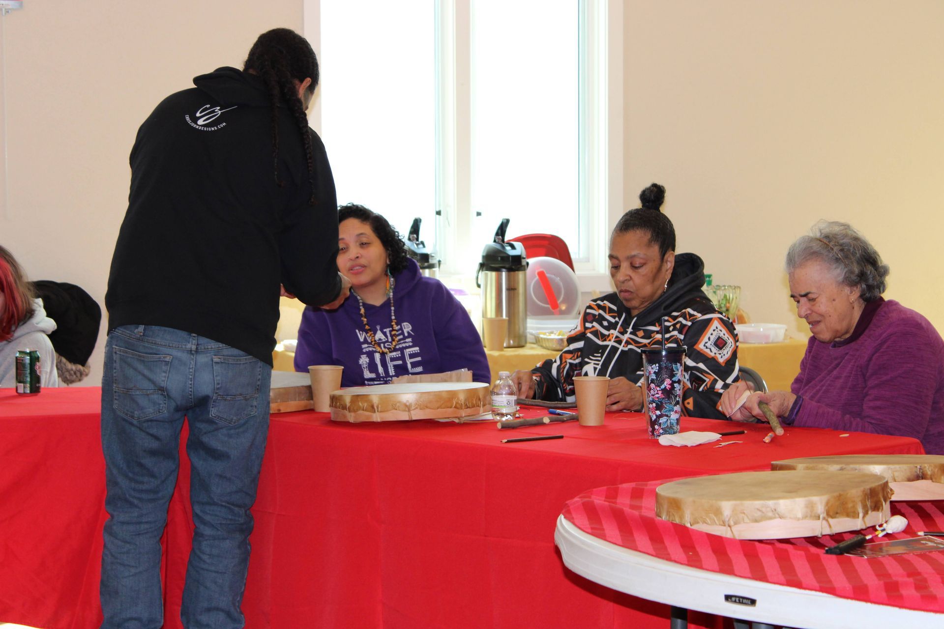 People crafting at tables in a brightly lit community hall.
