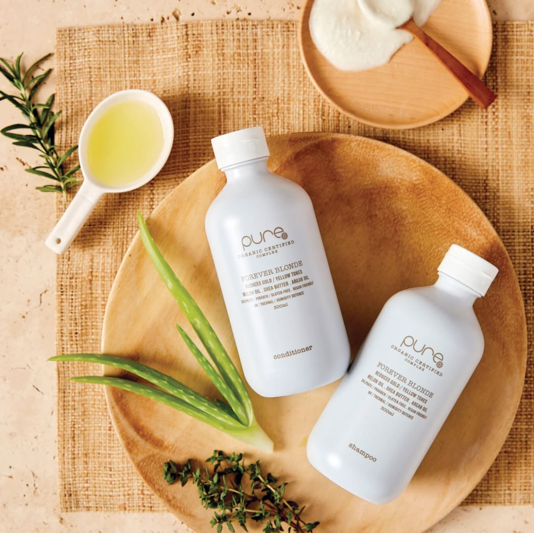 Bottles of Pure Beauty Products Are Sitting on a Wooden Plate — Hairdresser At Work in Cairns City, QLD