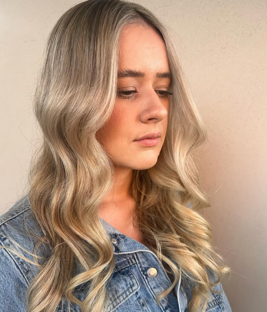 A Woman With Long Blonde Hair is Wearing a Black Tank Top — Hairdresser At Work in Cairns City, QLD