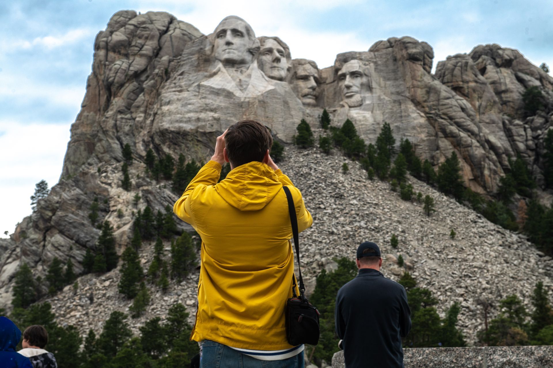 Man in yellow jacket photographing Mount Rushmore.
