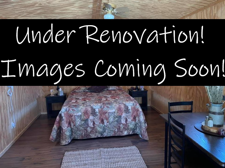 Interior of a room under renovation. Bed, nightstands, and a table are visible, with