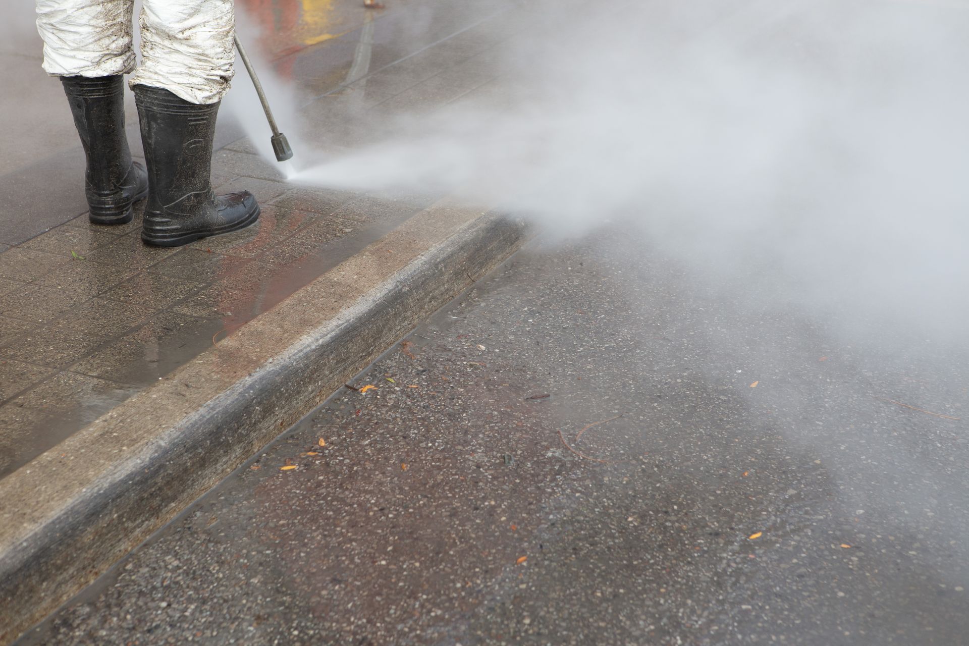 A man is cleaning graffiti on a blue garage door with a high pressure washer.