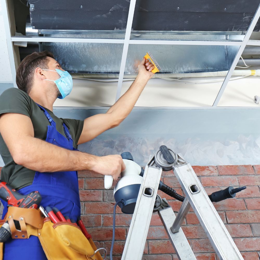 A man wearing a mask is working on a ceiling
