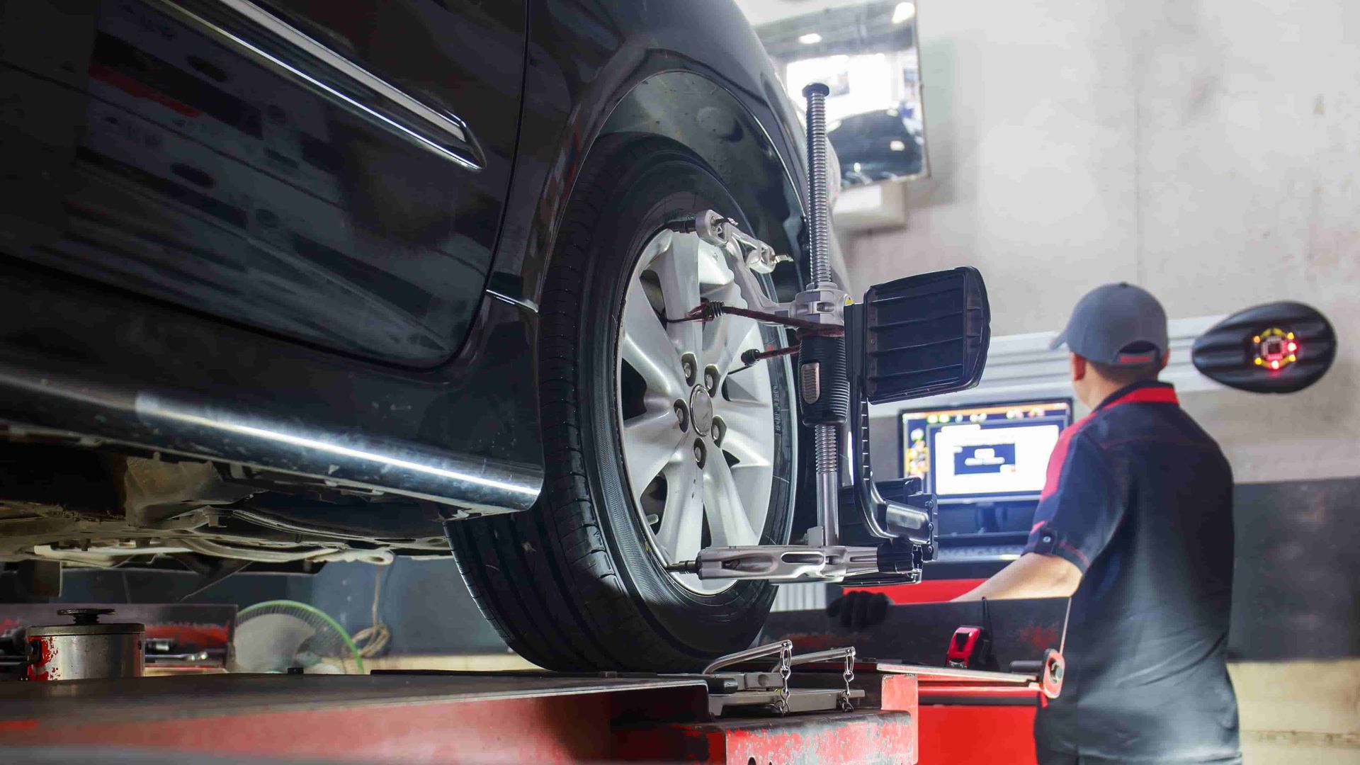 A Man Is Adjusting The Alignment Of A Car In A Garage — Reef Diesel Injection In Sarina, QLD