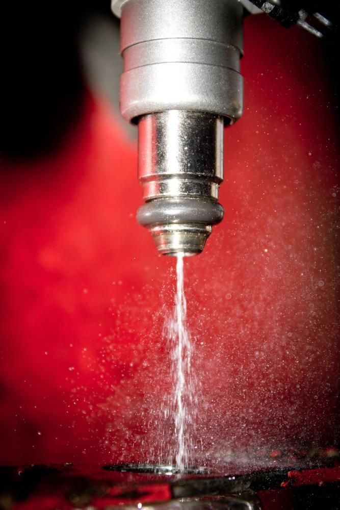 A Close Up Of A Fuel Injector Spraying Fuel On A Red Background — Reef Diesel Injection In Mackay, QLD
