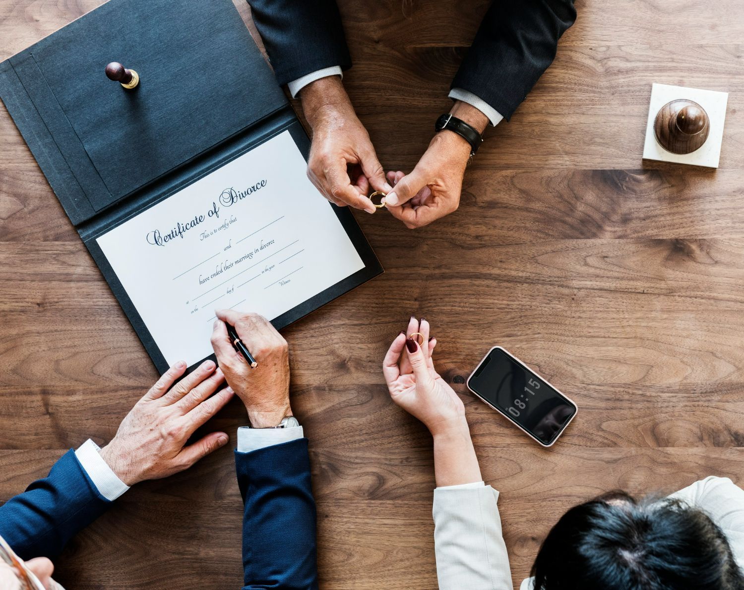 A man and a woman are sitting at a table signing a certificate of marriage.