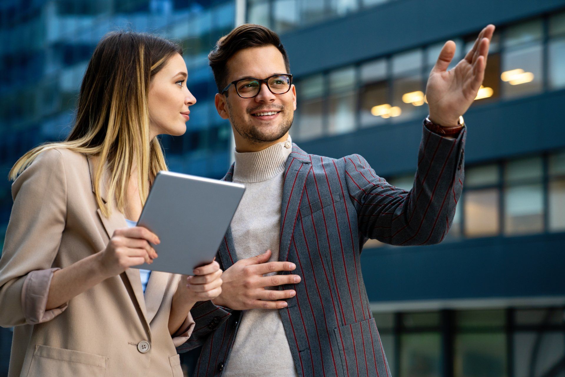 A man and a woman are standing next to each other looking at a tablet.