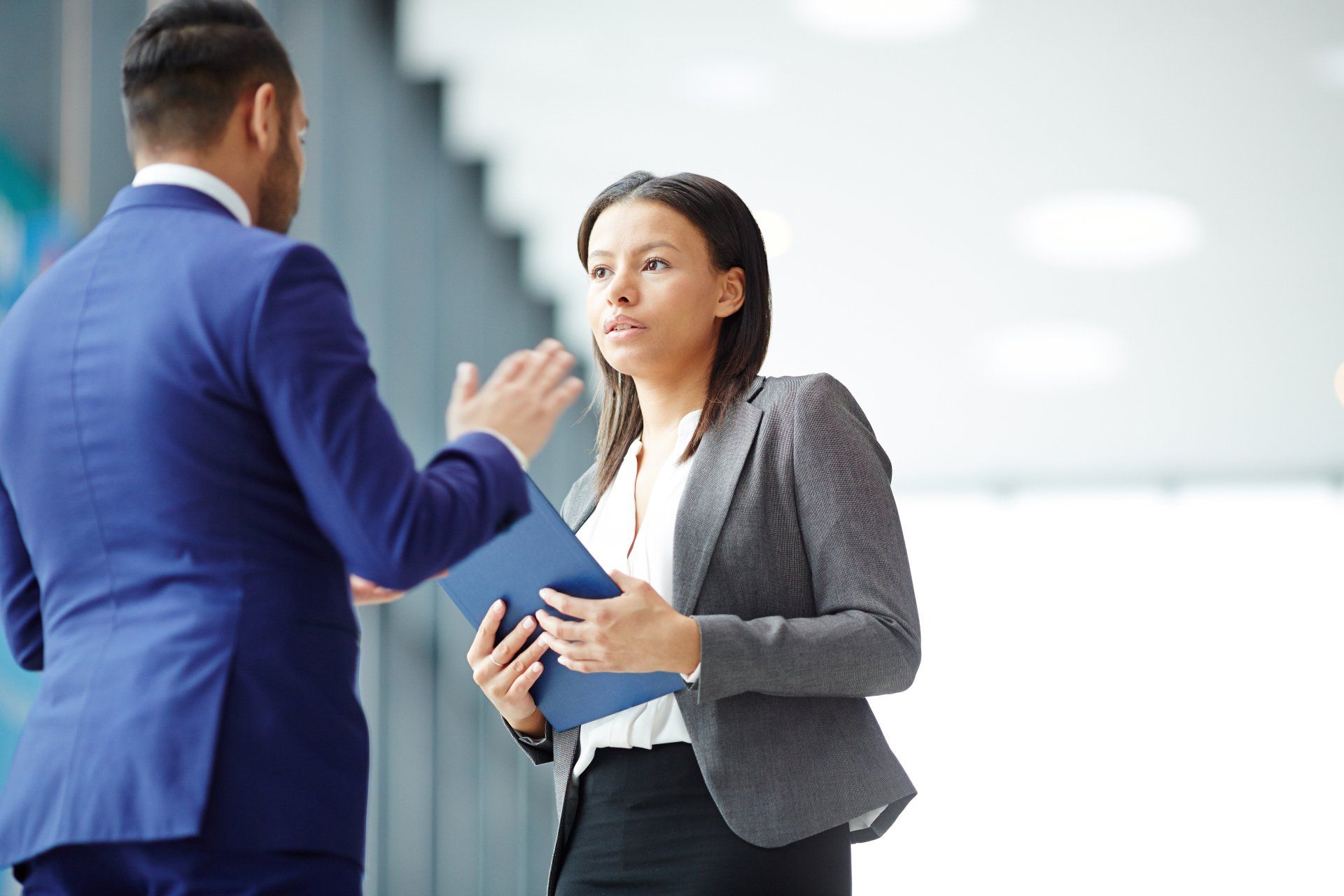 A man and a woman are talking to each other in an office.