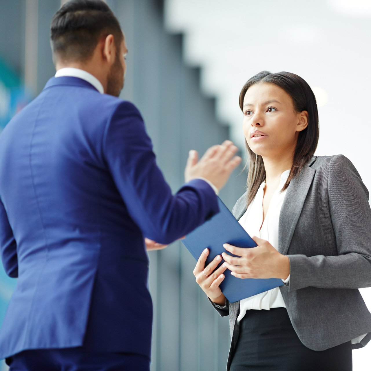 A man in a blue suit is talking to a woman in a gray jacket