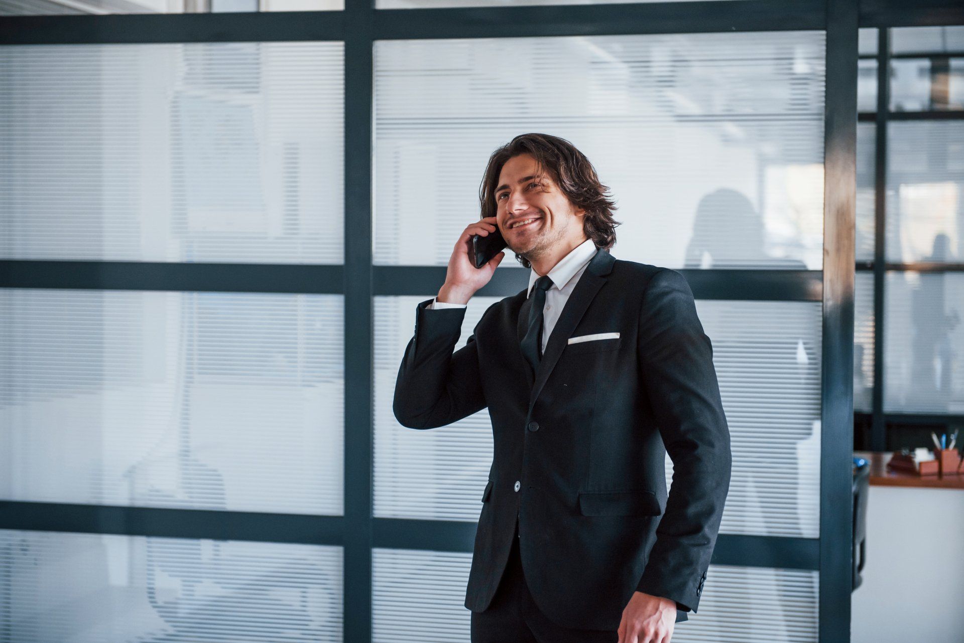 A man in a suit and tie is talking on a cell phone.