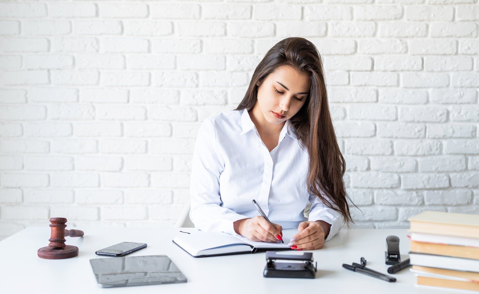 A woman is sitting at a desk writing in a notebook.