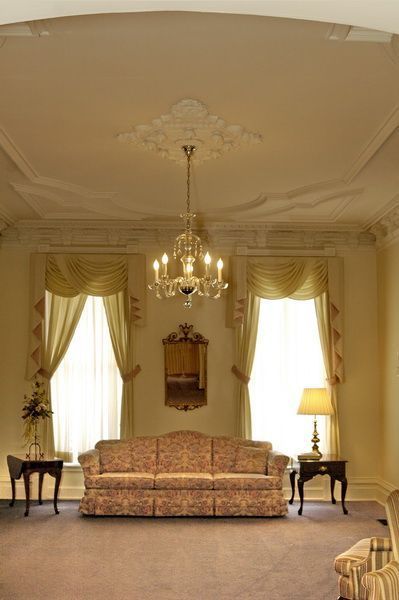 Formal room with couch, chandelier, and windows with drapes.