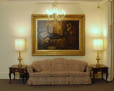 Living room with sofa, two lamps, a painting, and a chandelier.