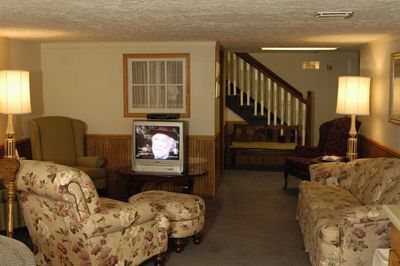 Living room with floral patterned furniture, lamps, and a TV, near a staircase.