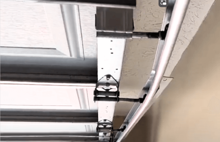 A close up of a metal rail track hanging from the ceiling of a garage door.