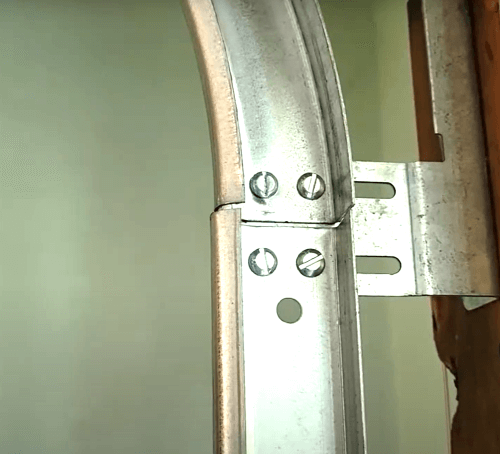A close up of a metal garage door track out of alignment