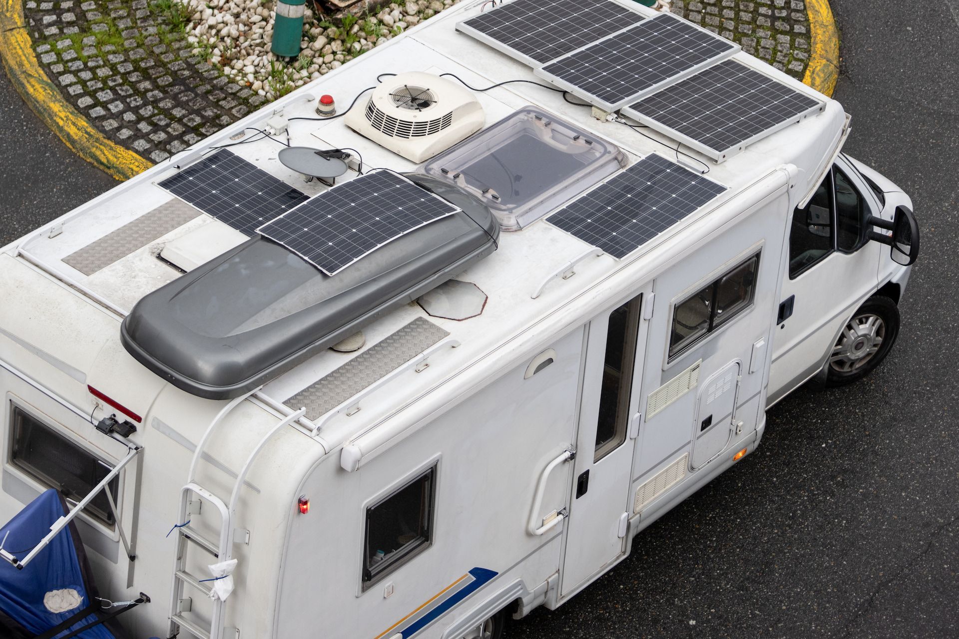 White RV With Solar Panels on Its Roof, Parked on Asphalt — Total Caravan Repairs in Forster, NSW