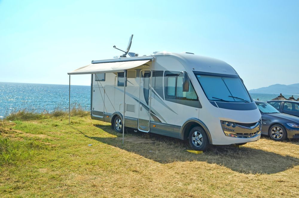 White RV Parked on Grass Near the Ocean Under a Sunny Sky — Total Caravan Repairs in Nabiac, NSW