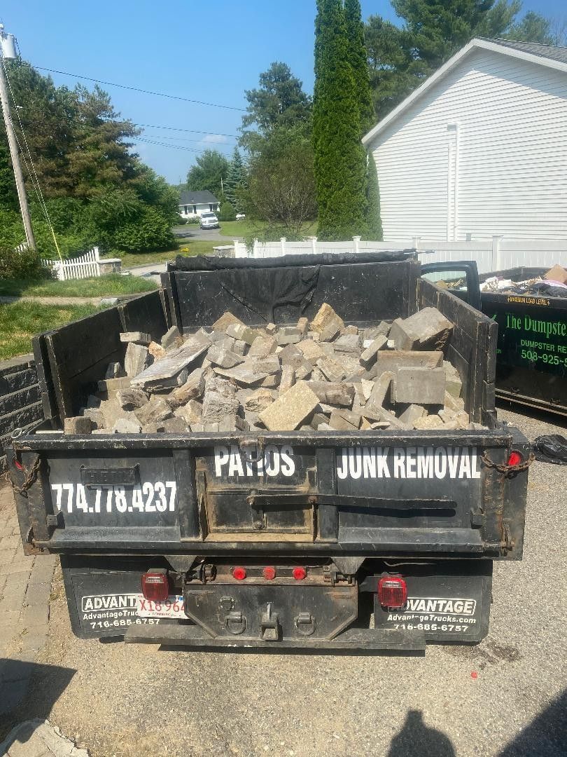 A dumpster filled with rocks is parked in front of a house.