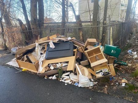 A pile of garbage is sitting on the side of a road.