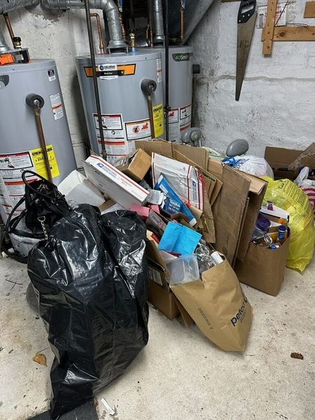 A room filled with boxes , trash bags , and water heaters.