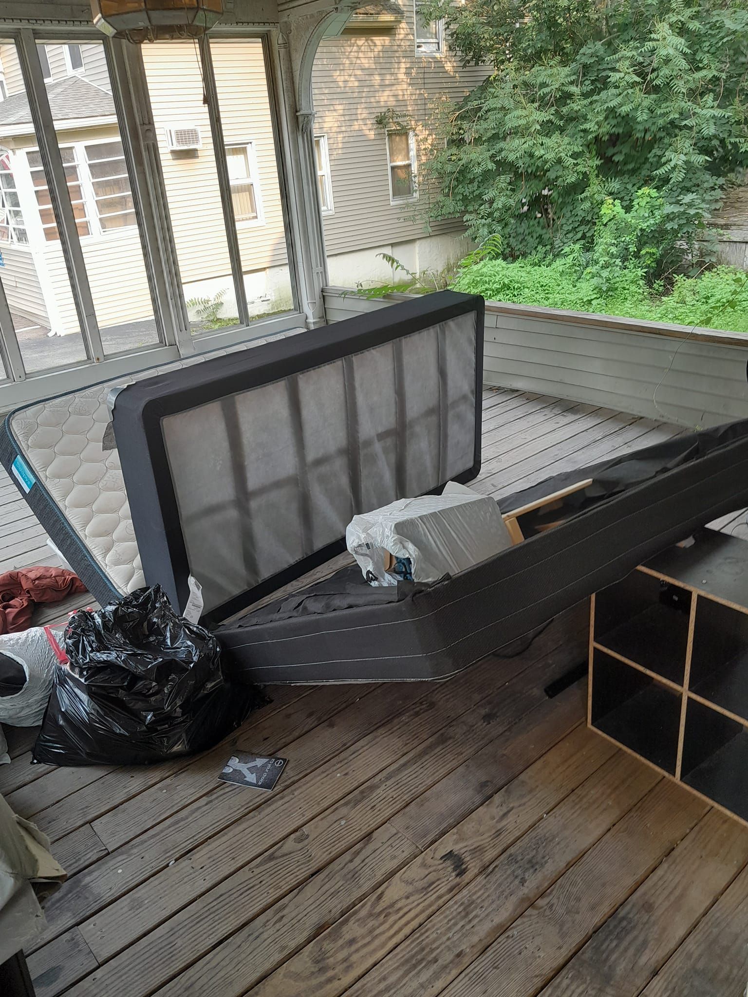 A mattress is laying on top of a wooden deck.