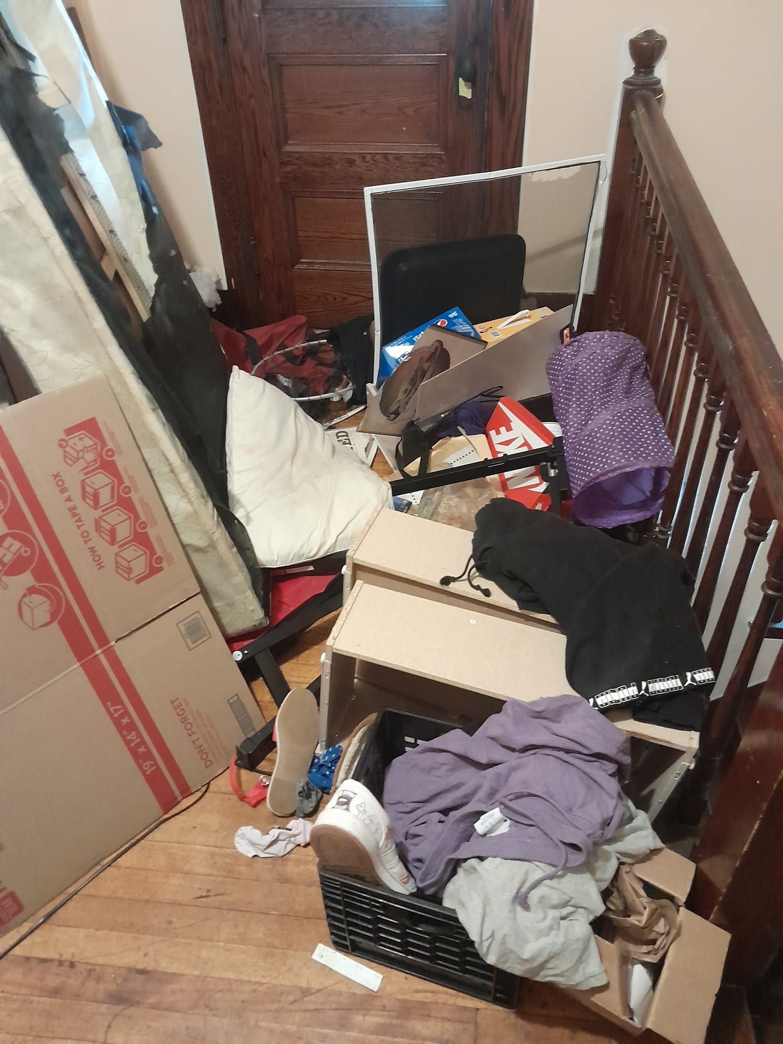 A room with a lot of boxes and clothes on the floor.
