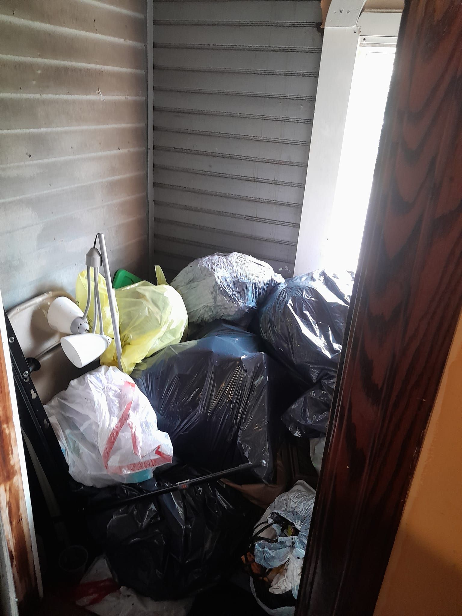 A room filled with lots of trash bags and clothes.
