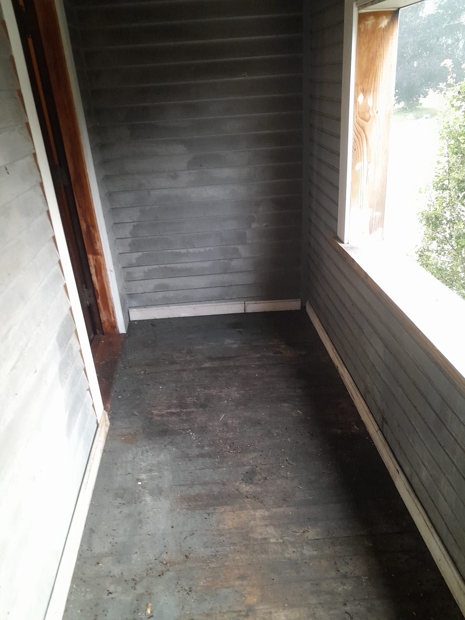 An empty room with a window and a wooden floor