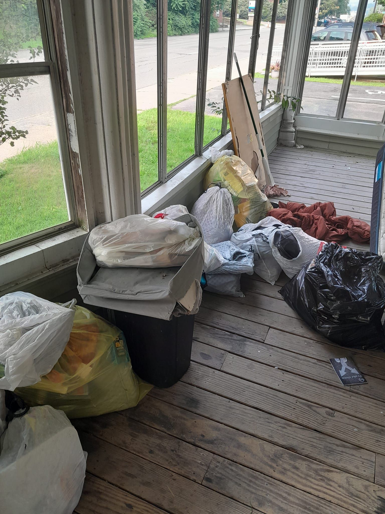 A room with a lot of trash on the floor and a window.