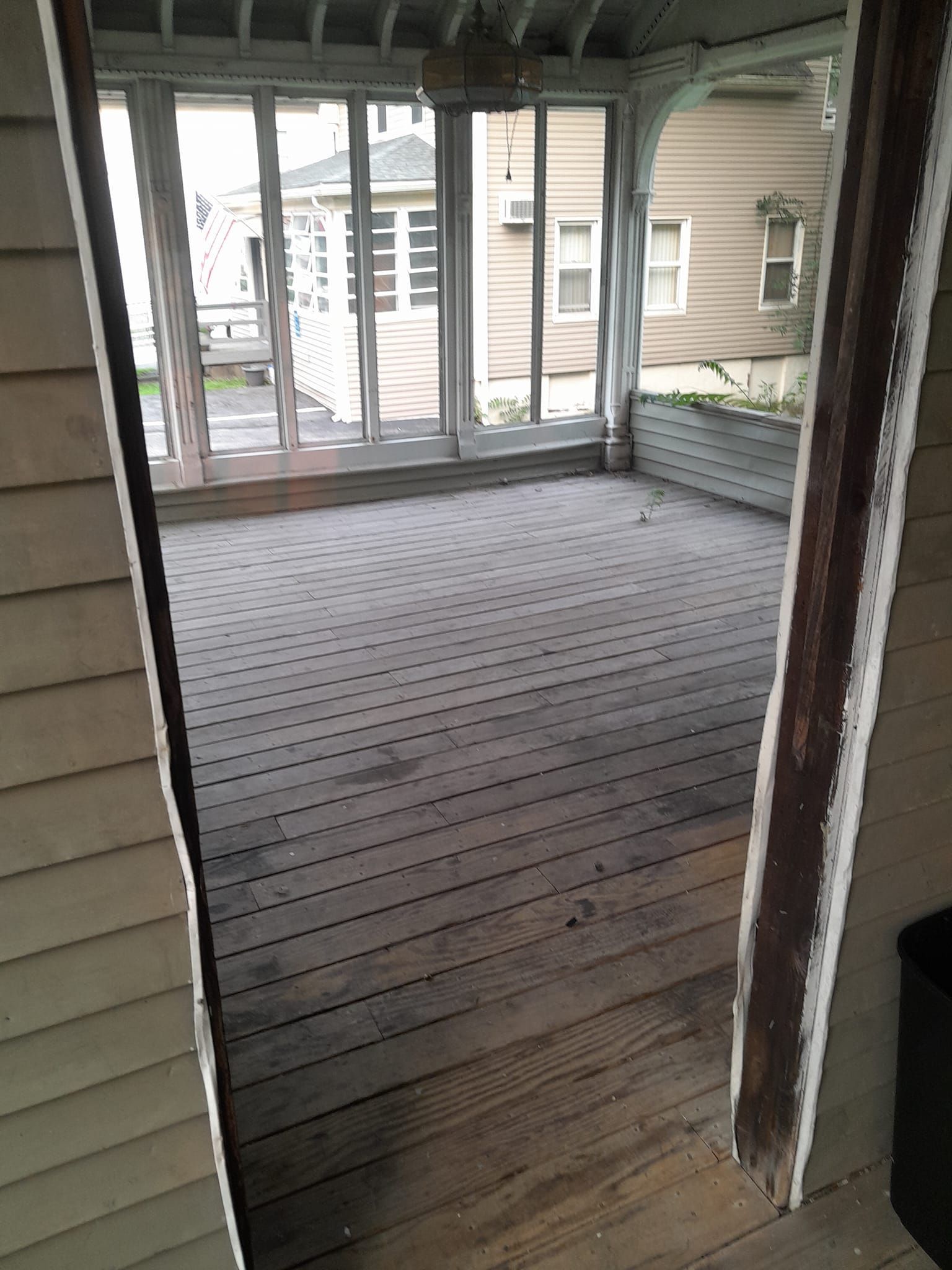 An empty screened in porch with a lot of windows
