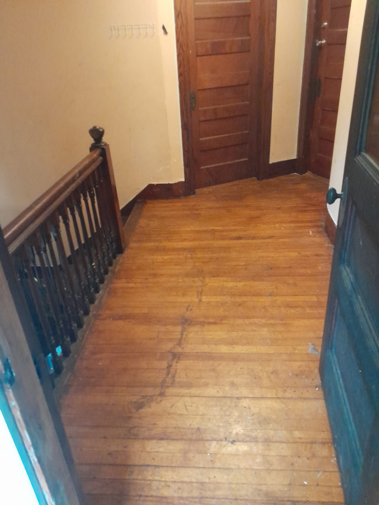 A hallway with wooden floors and stairs in a house.
