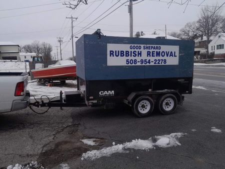 A truck is pulling a trailer that says rubbish removal