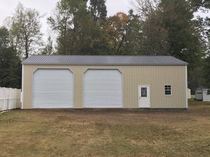 Beige metal garage with two bays, a door, and a small window.