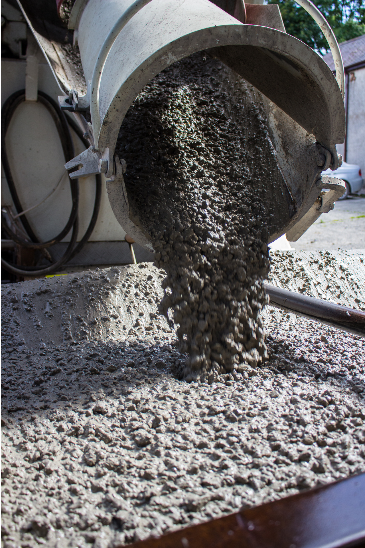 A bucket of concrete is being poured into a pile of gravel.