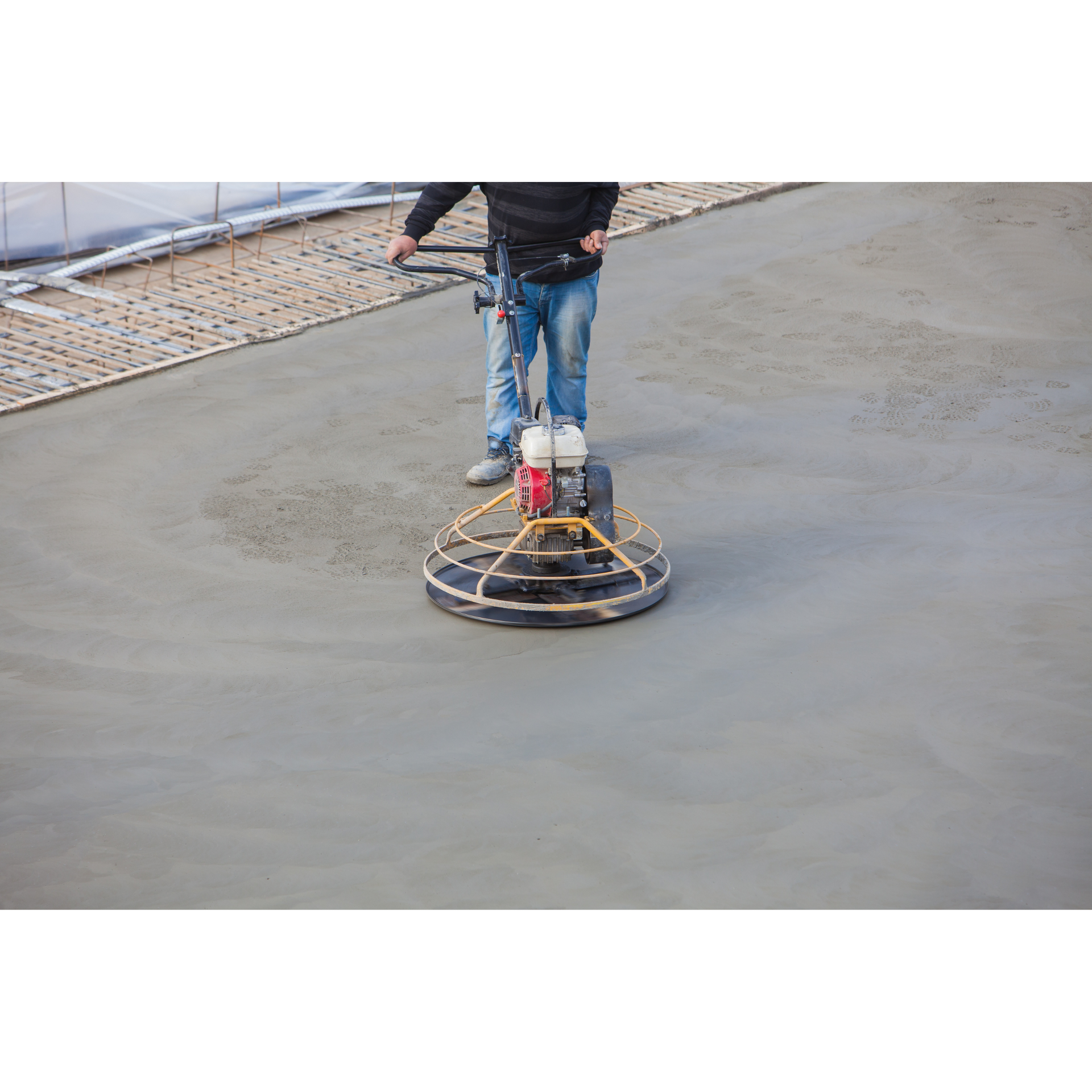 A man is using a machine to finish concrete on a construction site.