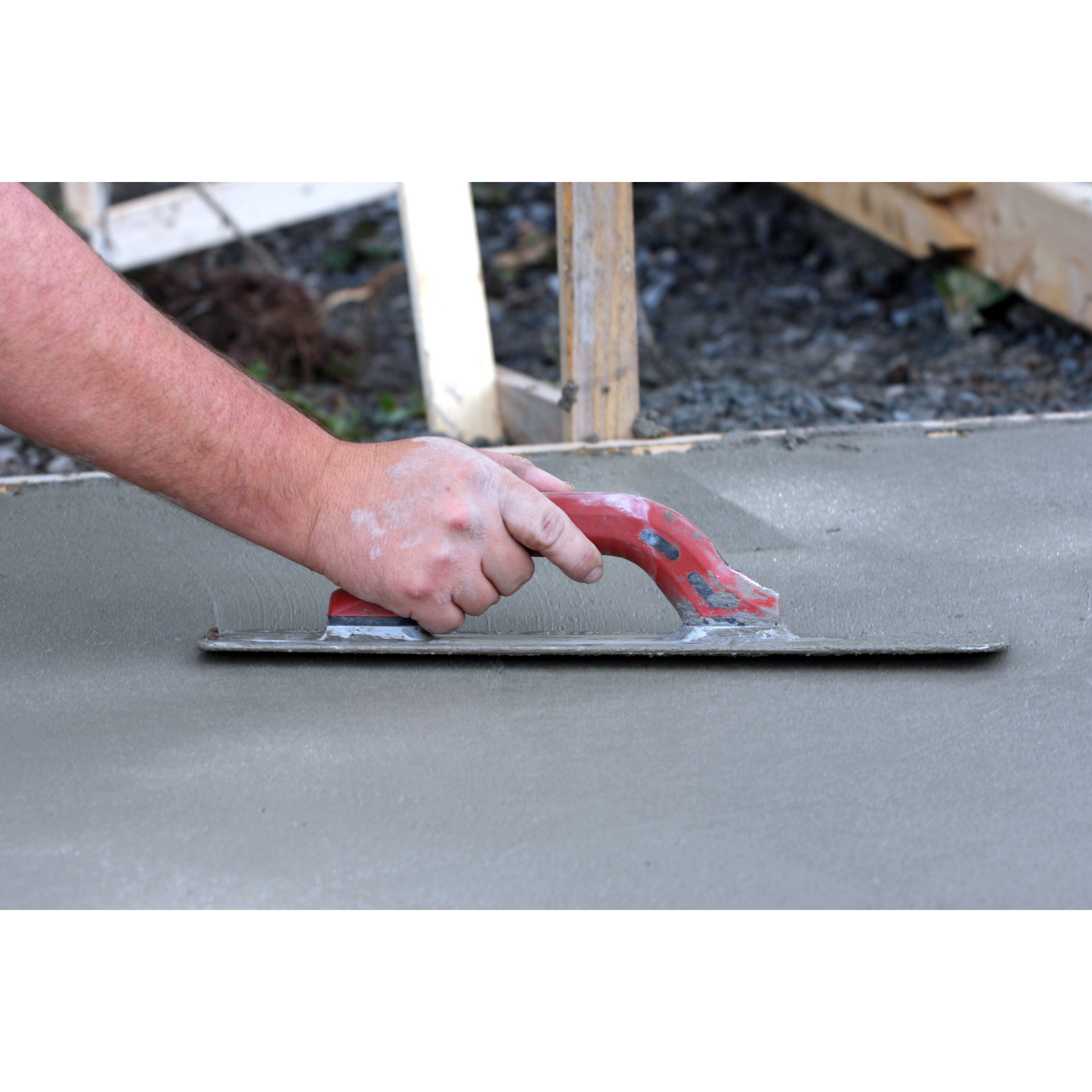 A person is troweling concrete on a sidewalk.