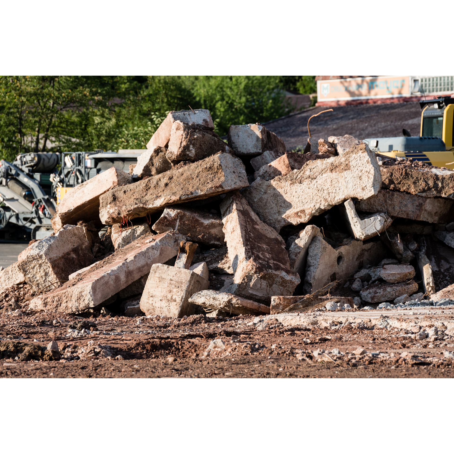 A pile of concrete blocks on a construction site with a bulldozer in the background.