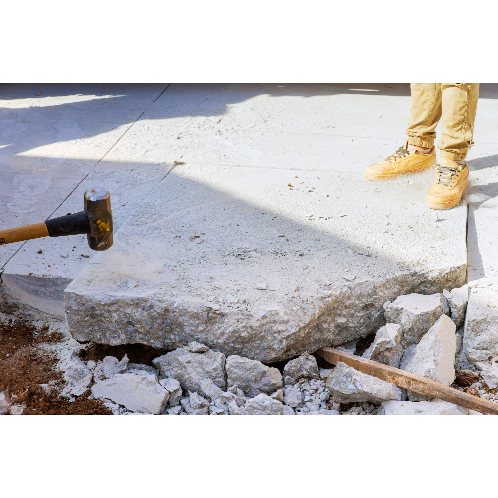 A man is breaking concrete with a hammer.