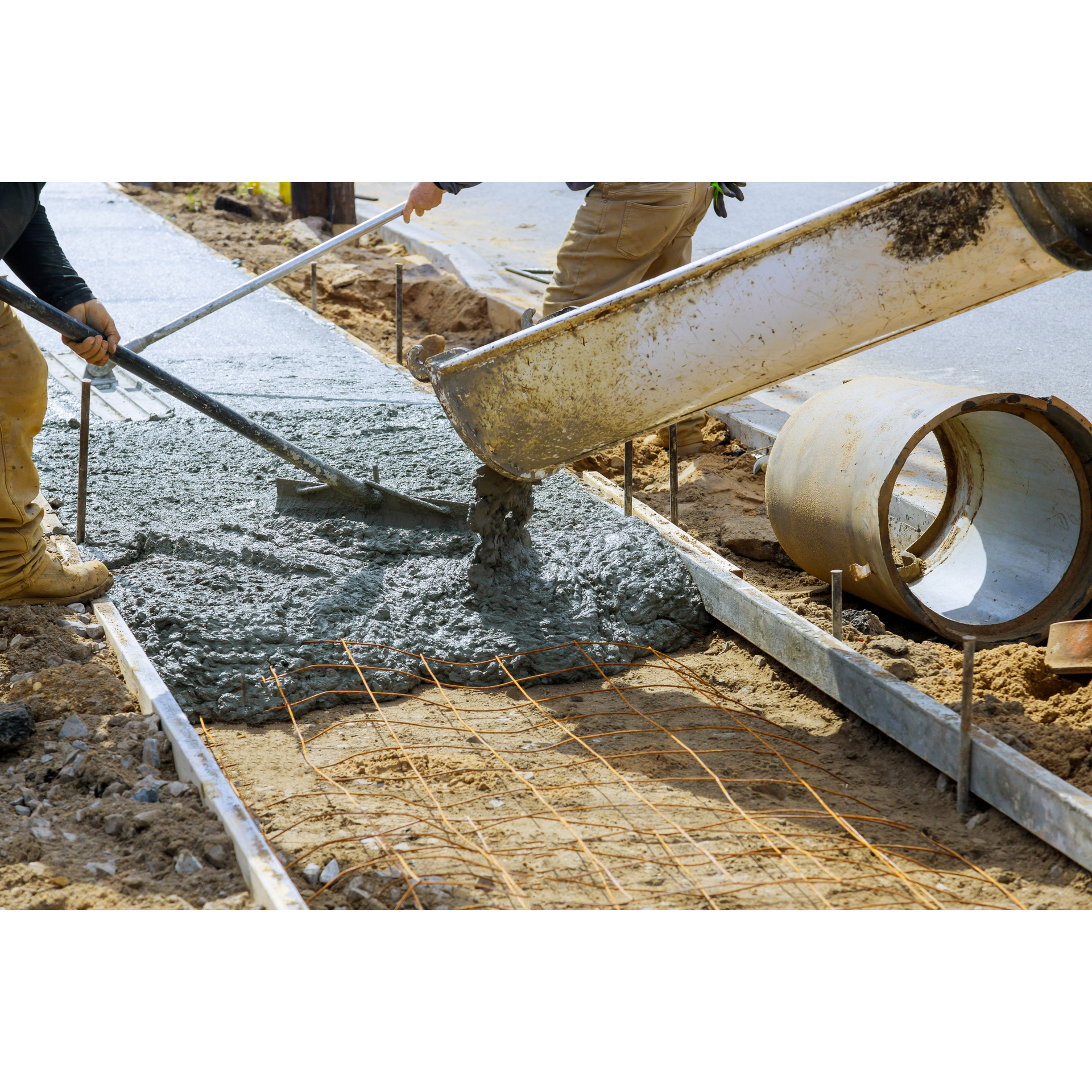 A man is pouring concrete on a sidewalk with a shovel.