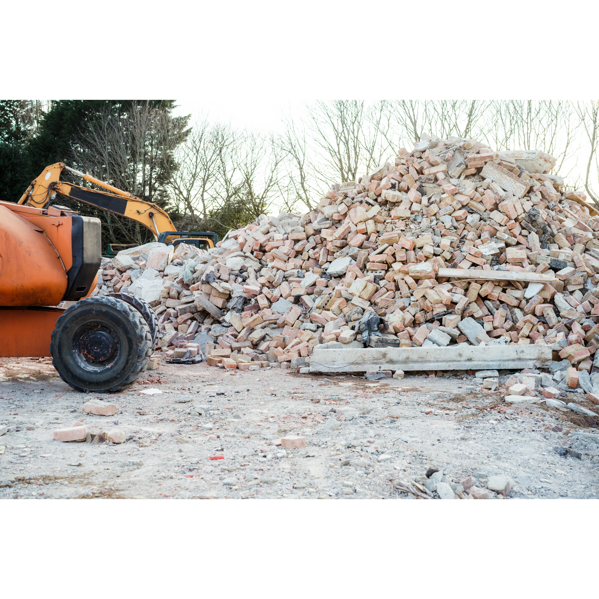 A pile of bricks is sitting next to a bulldozer on a construction site.