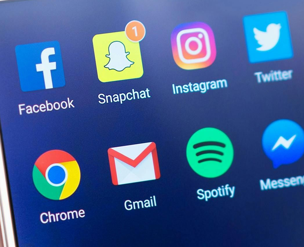 Smartphone screen with social media app icons: Facebook, Snapchat, Instagram, Twitter, Chrome, Gmail, Spotify, and Messenger.