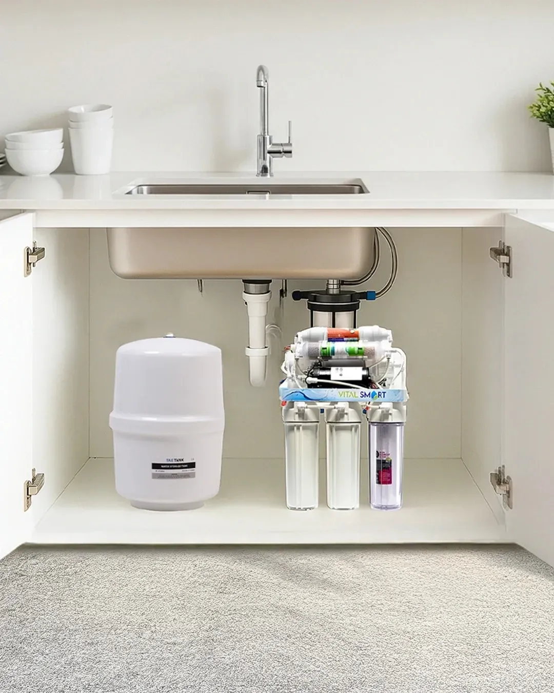 Système de filtration d'eau installé sous un évier de cuisine. Le réservoir blanc et les composants du filtre sont visibles.