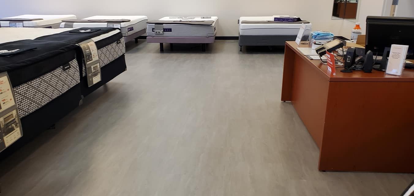 A showroom with multiple mattresses on display and a wooden desk with office supplies.