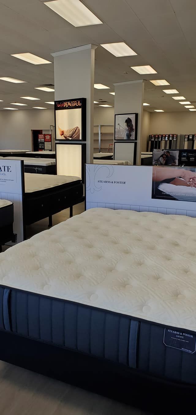 Mattress store interior with mattresses on display; bright overhead lights.