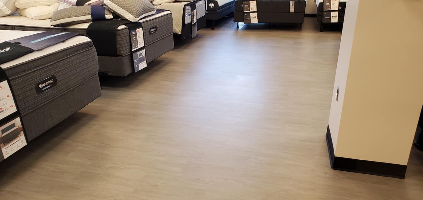 Mattresses on display in a store with light gray floors and a white pillar.