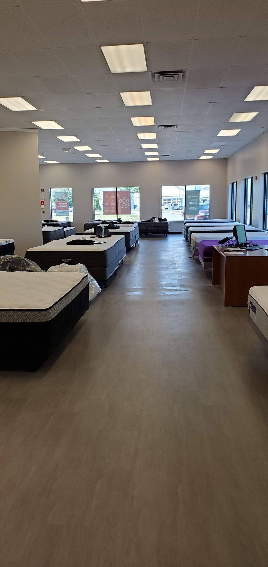 Interior of a mattress store with rows of beds and bright overhead lighting.