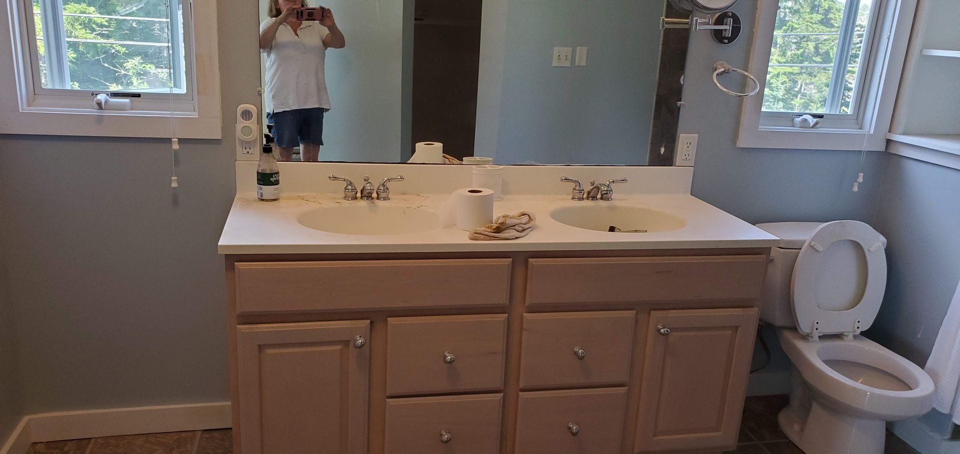 Bathroom with double sink vanity, toilet, and window.