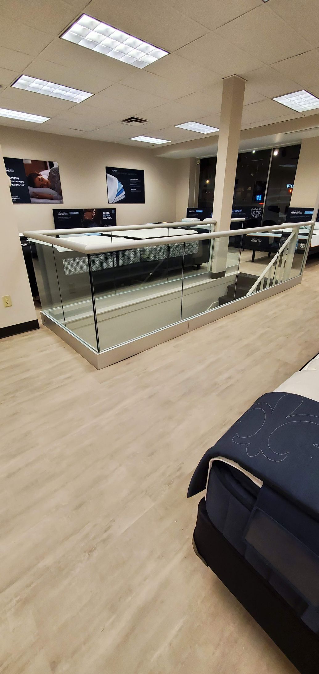 A store interior with a display case and a bed. The floor is light-colored wood.